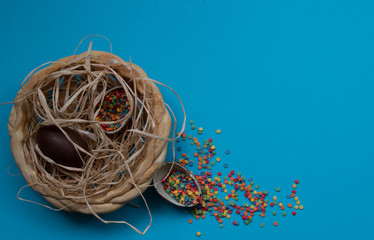 Easter chocolate eggs in a nest on a blue background