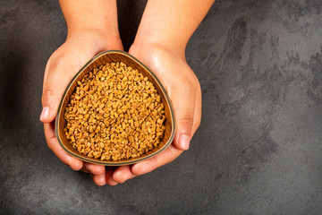 Trigonella foenum-graecum - Hands holding fenugreek seeds