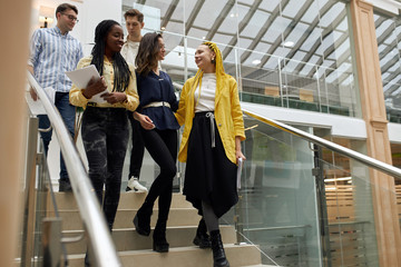 cheerful mixed race team leaving the office after working day, conversation, corporation, free time, spare time