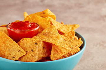 Mexican nachos or tortilla chips in a turquoise bowl with chili salsa dip sauce