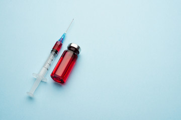 Medical vial and syringe on a light background. Red medicine in a bottle.