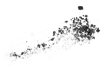 Small pieces of charcoal dust on a white background, top view.