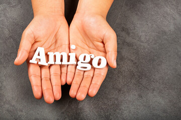 Hands holding wooden letters word Amigo in Spanish language
