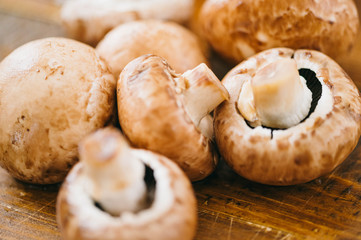 Horizotal photo of pile of small fresh organic mushrooms champignons on wooden board table. Stuffed mushrooms, covered in herbs. Ingredients with fresh mushrooms on wooden background