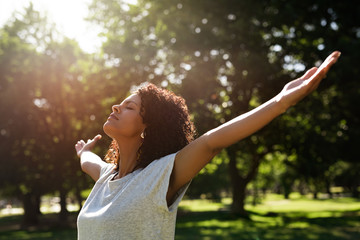 Woman standing in a park rasing her arms skyward
