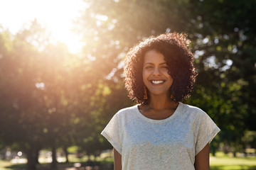 Smiling young woman standing in a park in the summer