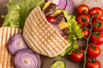 Pita doner kebab with green salad, potato free, tomatoes, cherry, cucumber and fried beef. Street food. Fast food. Doner kebab