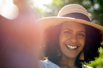 Smiling woman wearing a sun hat and talking selfies