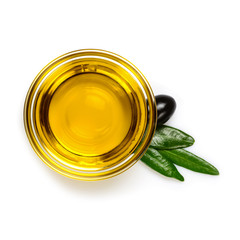 Olive oil. Extra virgin olive oil in glass transparent bowl with leaves and one black olive. Close-up, isolated on white background.