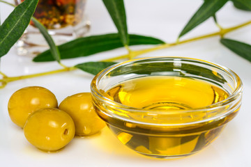 Olive oil. Greek olive oil in glass transparent bowl with leaves and marinated olives. Close-up, isolated on white background.