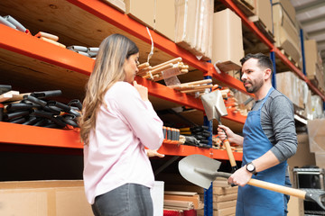 Worker Explaining About Tools To Woman At Warehouse