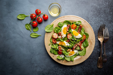 Salad with spinach, sun-dried tomatoes and eggs. Healthy home made food. Concept for a tasty and healthy meal. Top view. Copy space.