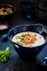 Tom Yum Kung soup, a Thai traditional spicy prawn soup in a bowl on dark background