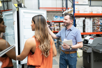 Fototapeta na wymiar Male Employee Standing By Female Customer Looking At Machine