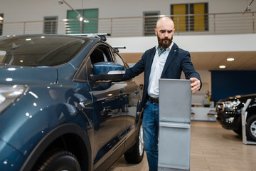 Man studies the configuration, car dealership