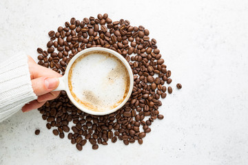Cup of coffee in womens hand on white background, top view
