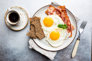 Fried eggs and bacon for breakfast on a plate, top view, copyspace