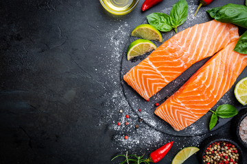 Raw salmon fillet and ingredients for cooking, seasonings and herbs on a dark background . Top view