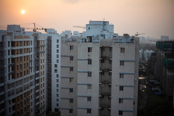 A series of real estate high rise buildings in a township under the sky during sunset. Indian city and architecture.