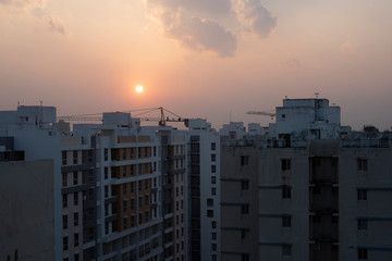 A series of real estate high rise buildings in a township under the sky during sunset. Indian city and architecture.