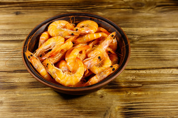 Fresh raw shrimps in a ceramic bowl on a wooden table