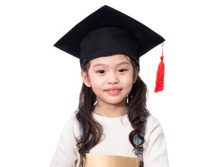 Asian little cute girl 6 years old wearing graduation hat and holding a book on hands. Preschool lovely kid with a book isolated on white background with clipping path.