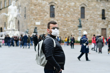 Obraz premium Coronavirus Covid-2019 in Italy. Man in a protective medical mask on a street in a city in Florence Italy. Streets and squares of Italy without tourists.