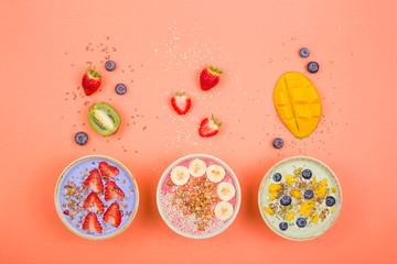 Beautiful multi-colored healthy smoothie bowls with berries and superfoods on a bright background. Summer food for detox concept.