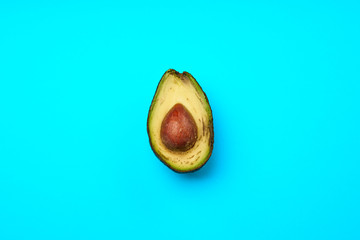 A rotten avocado cut in half on blue background. Avocado is rotten and no longer good to eat.