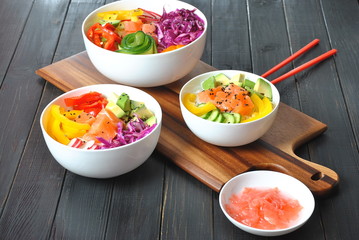 Poke bowls with fresh salmon, crystal noodles, radish, avocado, sweet pepper, cucumber, sesame seeds, red cabbage. Organic food. Fresh seafood recipe. Food concept poke bowl on wooden background