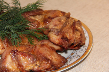 Fried quail with dill on a white plate. Tender dietary meat. Linen background.