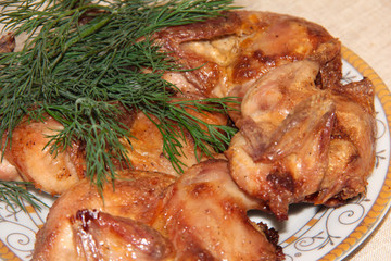 Fried quail with dill on a white plate. Tender dietary meat. Linen background.