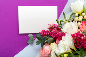 Flowers mock up gift card. Congratulations card in bouquet of roses, tulips, eucalyptus on purple background. White blank card with space for text, frame mockup for invitation. Spring festive flowers.