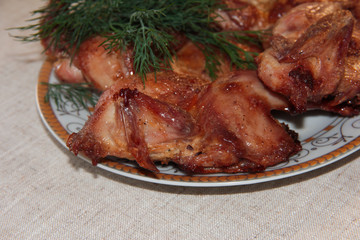 Fried quail with dill on a white plate. Tender dietary meat. Linen background.
