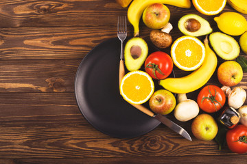 Intermittent fasting concept. Black plate on a wooden table with food, located at the time of the period of nutrition and fasting. Top view, flat lay.