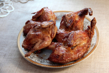 Fried quail with dill on a white plate. Tender dietary meat. Linen background.