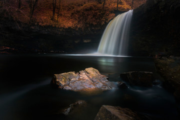 A dark and moody long exposure of the waterfall known as Lady Falls or Sgwd Gwladus on the river Afon Pyrddin near Pontneddfechan, South Wales, UK