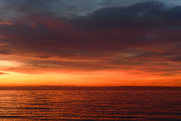 Orange sunrise over the sea. Dramatic sky clouds.