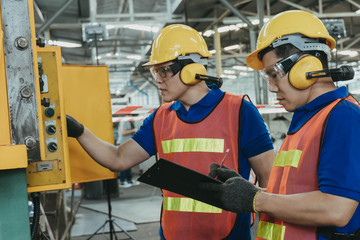 Engineer or mechanical worker with yellow safety helmet checking on production in a factory. Industrial, Mechanic, Engineering Concept. 