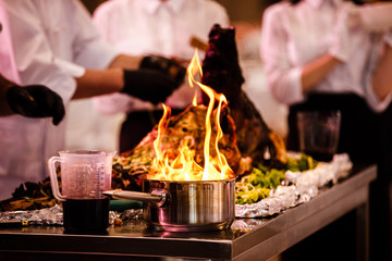 Cooking show, the cook prepares food in a frying pan with fire. The chef prepares food with fire show in the restaurant. selective focus