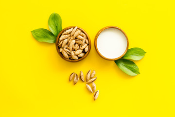 Alternative milk made from almond. Drink near unpeeled on yellow table top-down