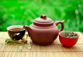 Chinese tea ceremony in the garden with dry green tea in scoop on a wooden table.