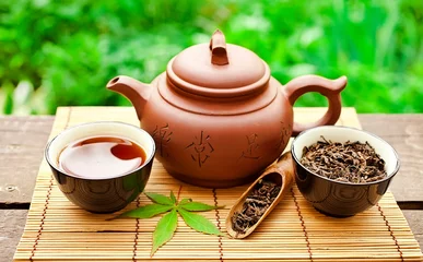 Foto op Aluminium Chinese tea ceremony in the garden with dry green tea in scoop on a wooden table. © Snowbelle