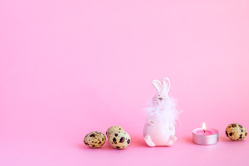 Festive still life made of bunny, quail eggs and candle. Copy space. Holidays concept.