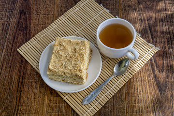 Cup of tea with cake on brown table background