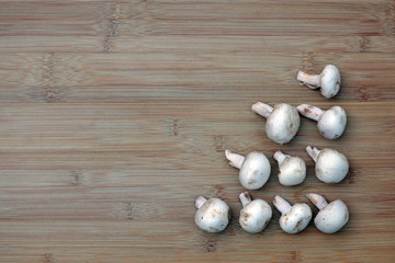 White mushrooms arranged in a triangle on the lower right of a bamboo board