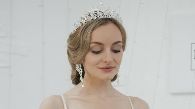 Close up shot of young blonde bride with gorgeous wedding hairstyle in tiara earrings turning head showing gorgeous wedding makeup and hairdo spinning around teasing and seductively looking in camera