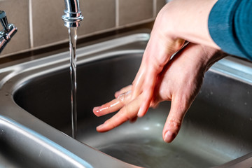 Proper washing of hands demonstrated at steel kitchen sink