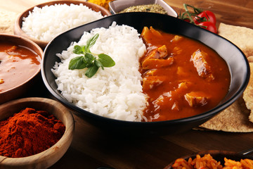 Chicken tikka masala spicy curry meat food in pot with rice and naan bread. indian food on table