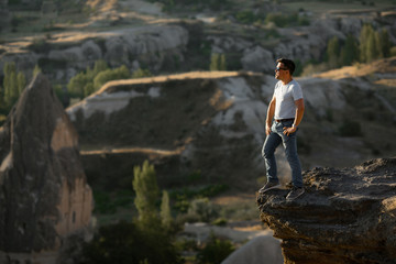 man stands on cliff and looks into the distance.